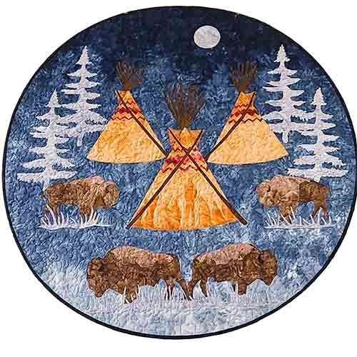 A small round quilt with bison, trees and teepees on a blue background